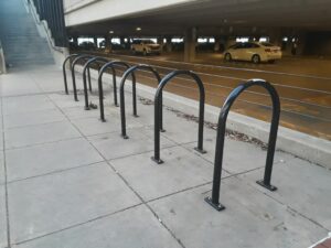 Arceaux de stationnement vélo près d’un immeuble et d’un parking