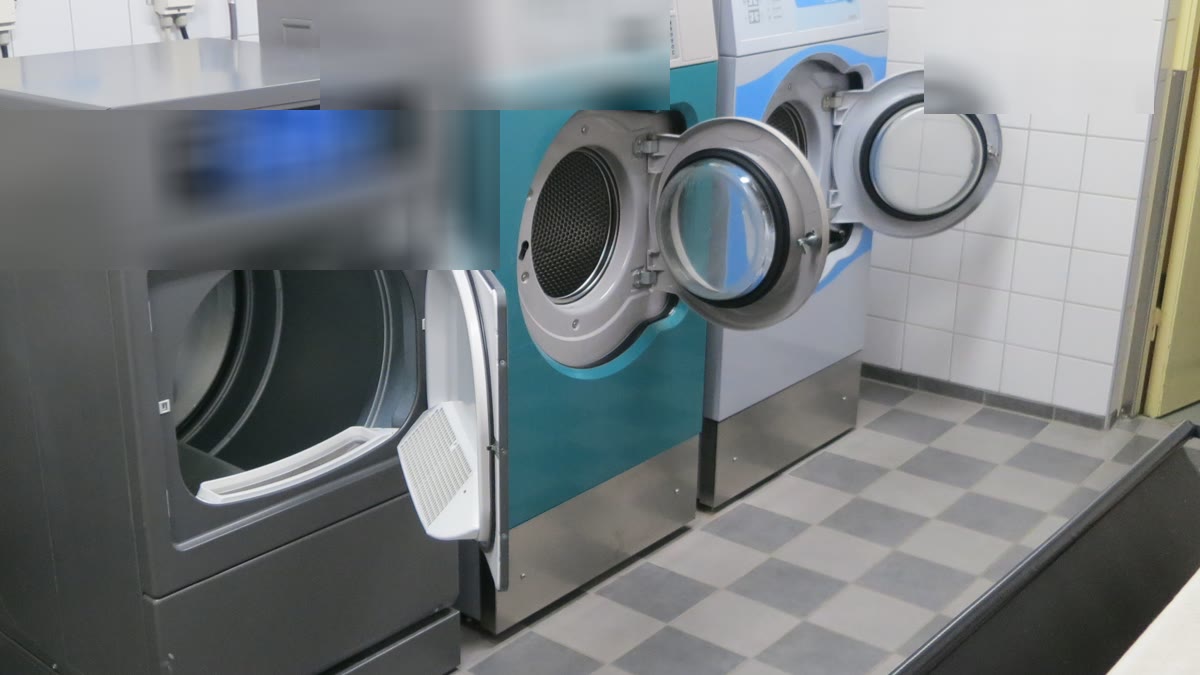 Buanderie collective propre avec lave-linge ouverts et sol carrelé