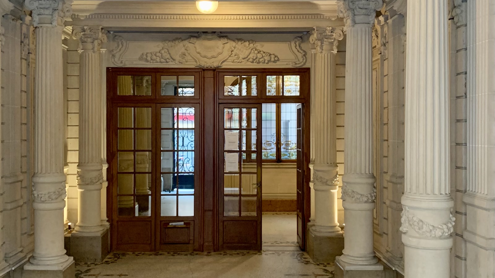 Hall d’immeuble ancien avec porte vitrée et boiseries