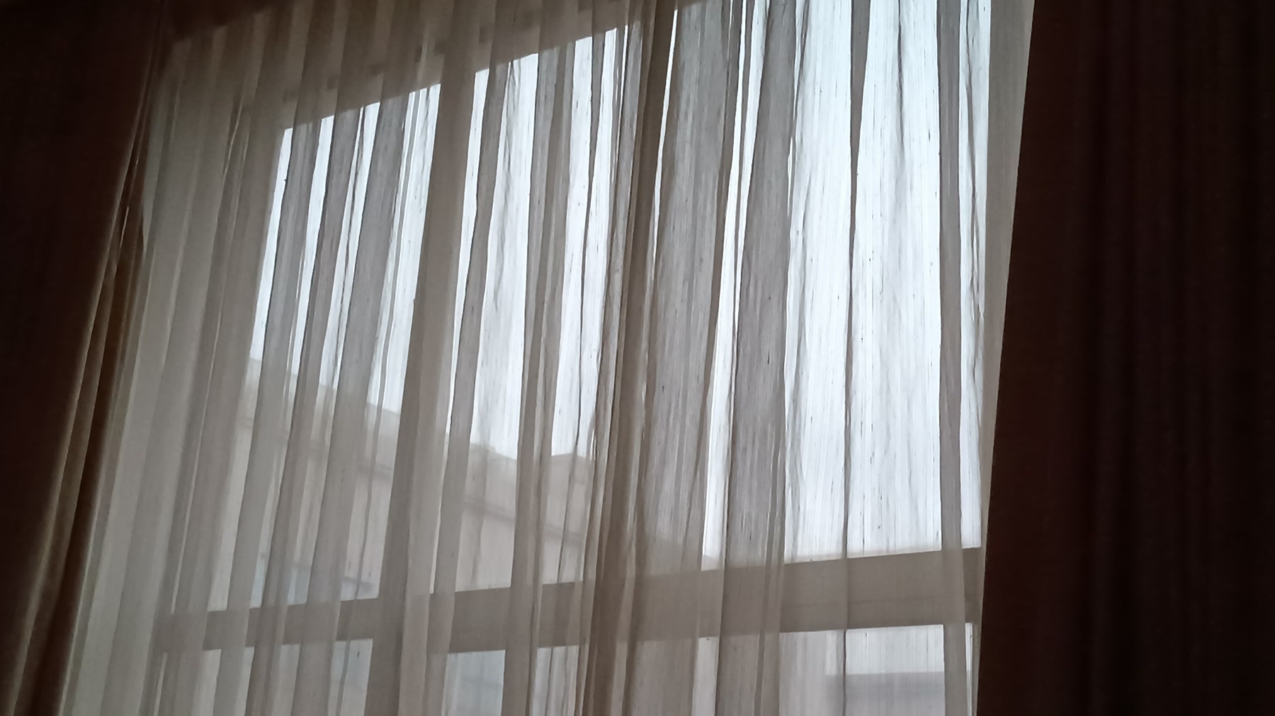 Voilages clairs devant une fenêtre dans un logement aéré
